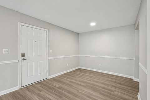 A room with a white door and wooden flooring.