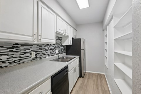 A kitchen with white cabinets and a black fridge.