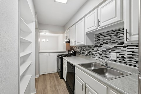 A modern kitchen with white cabinets and a black and white backsplash.