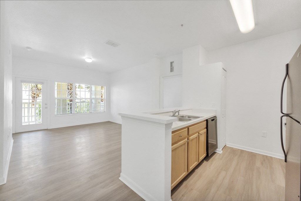 a kitchen and living room with hardwood floors and white walls