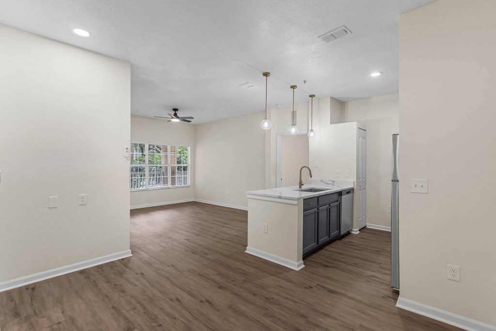 an empty living room and kitchen with a large window