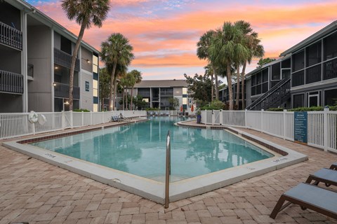 A pool surrounded by buildings and palm trees.
