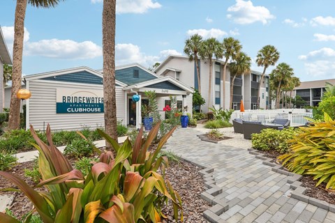 A building with a sign that says "Bringavate Clubhouse" is surrounded by palm trees and plants.