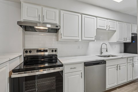 A kitchen with white cabinets and a black stove top oven.