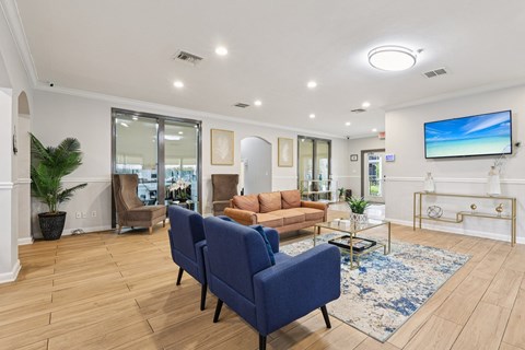 A living room with a blue sofa and a television on the wall.