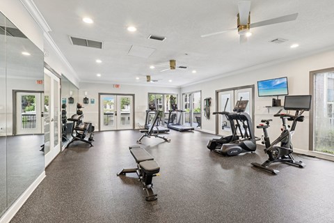 A spacious gym with a variety of exercise equipment and a ceiling fan.