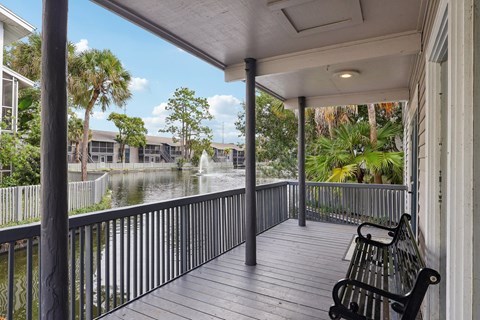 A porch with a bench and a view of a lake.