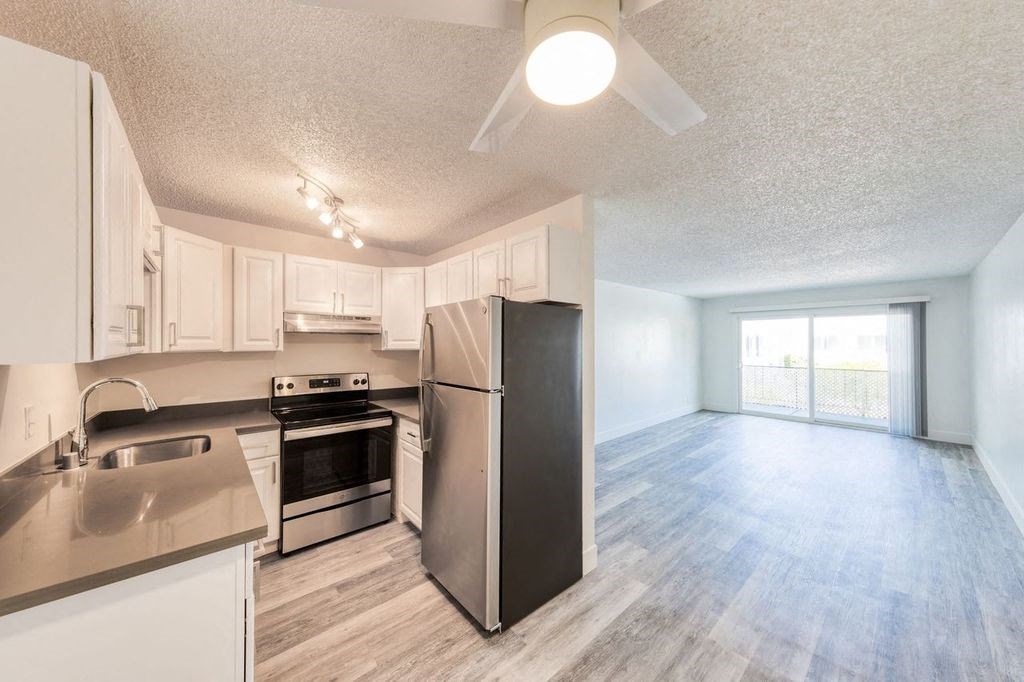 an empty kitchen and living room with a ceiling fan