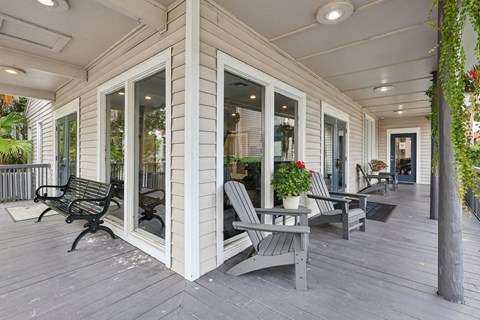 A white house with a grey deck and a black bench.