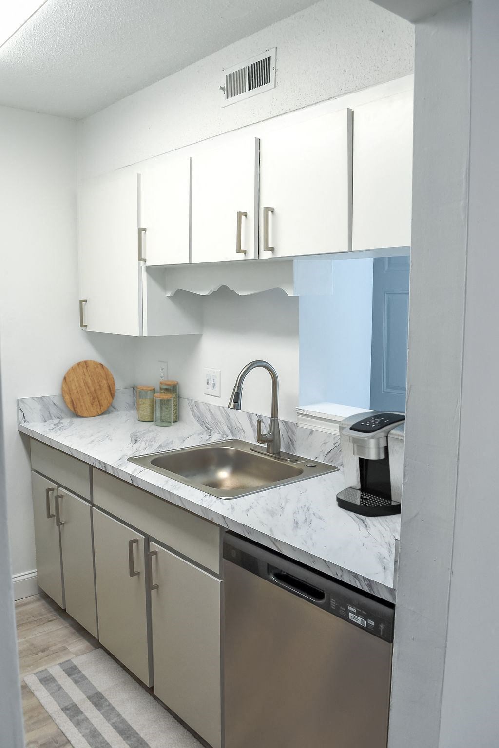 a kitchen with white cabinets and a stainless steel sink