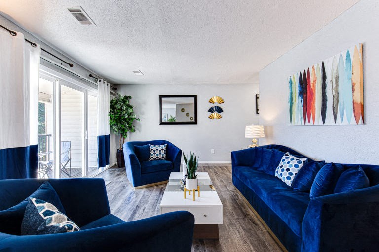 a living room with blue couches and chairs and a white coffee table with a plant on