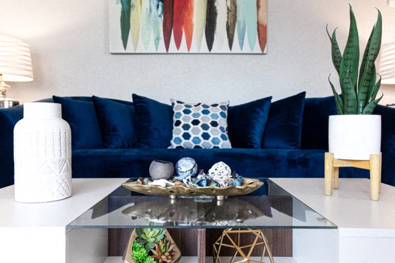 a living room with a blue couch and a glass coffee table