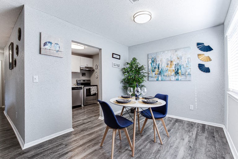 a dining area with a table and chairs and a kitchen in the background