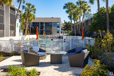 an outdoor patio with chairs and tables next to a pool