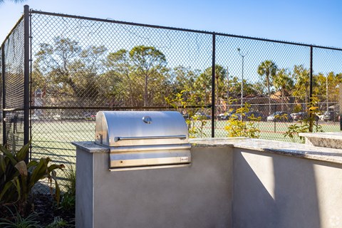 a grill on a wall next to a tennis court with a fence