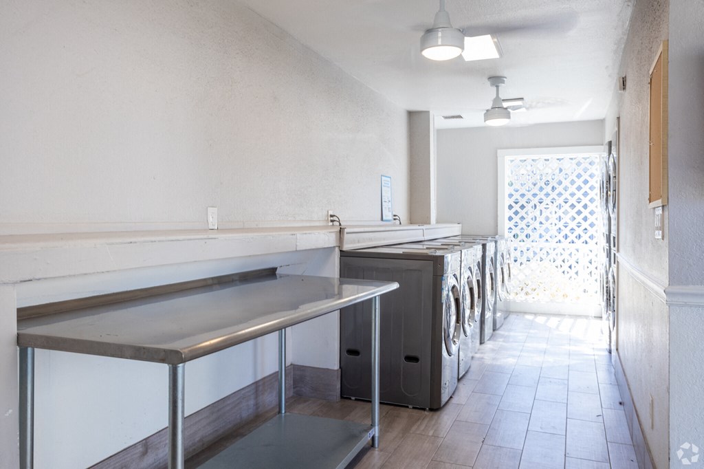 an empty laundry room with stainless steel counters and a row of washing machines