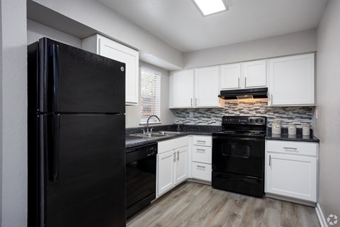 an empty kitchen with black appliances and white cabinets