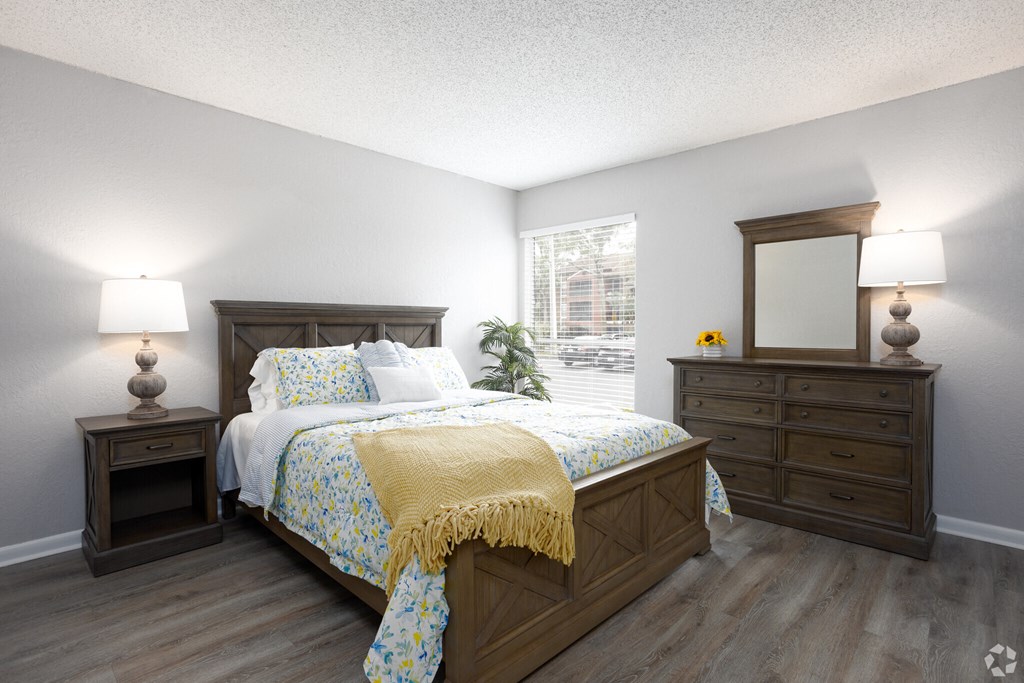 a bedroom with a bed and dressers and a window