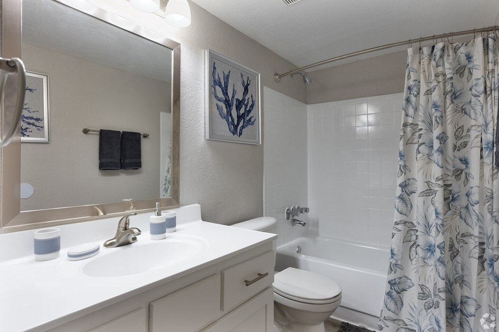 a white bathroom with a shower curtain and a white sink and toilet