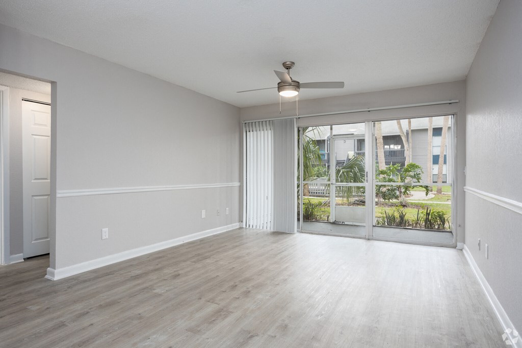 an empty living room with a window and a ceiling fan