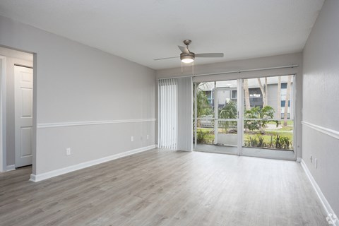 an empty living room with a window and a ceiling fan