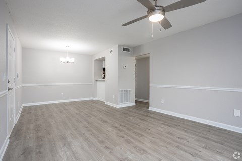 an empty living room with wood flooring and a ceiling fan