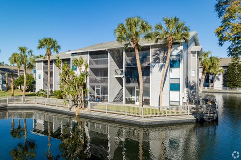 a building with palm trees next to a body of water