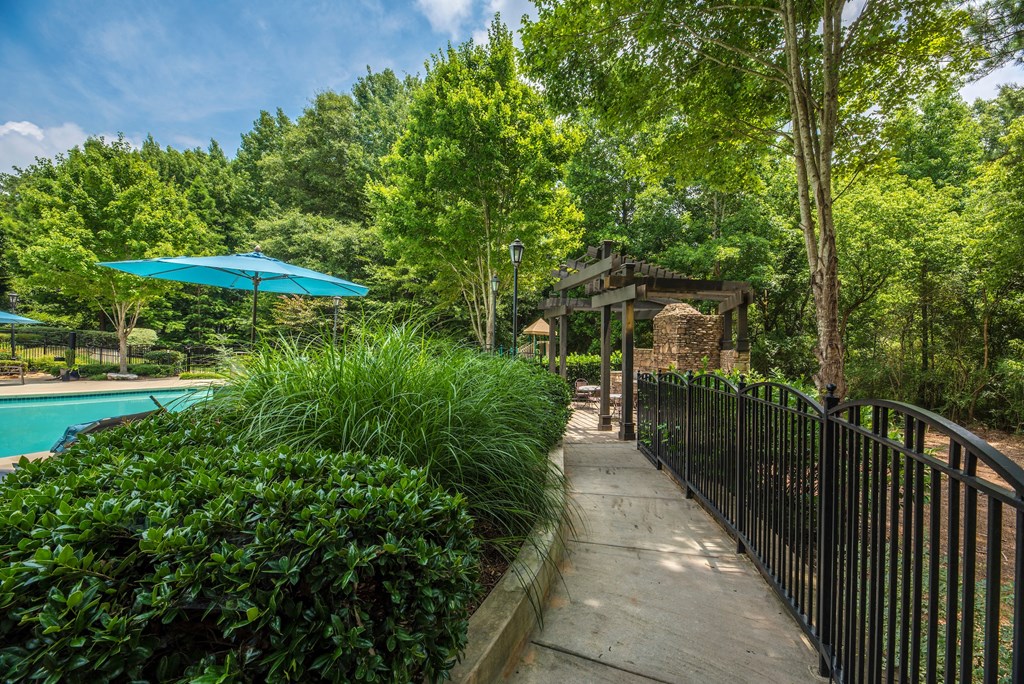a walkway next to a pool with a gazebo and a fence