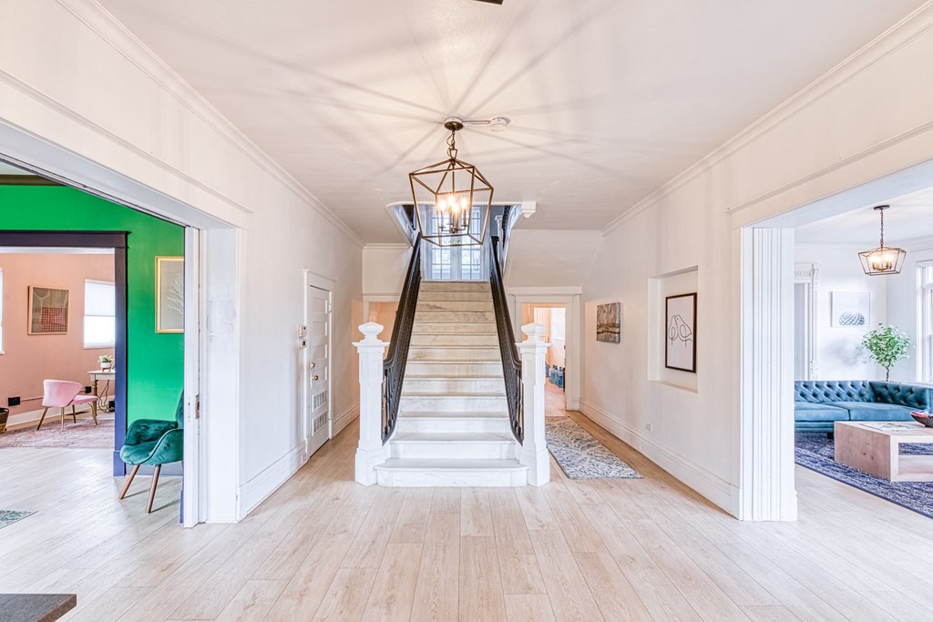 a living room with a staircase and a green wall and a ceiling fan