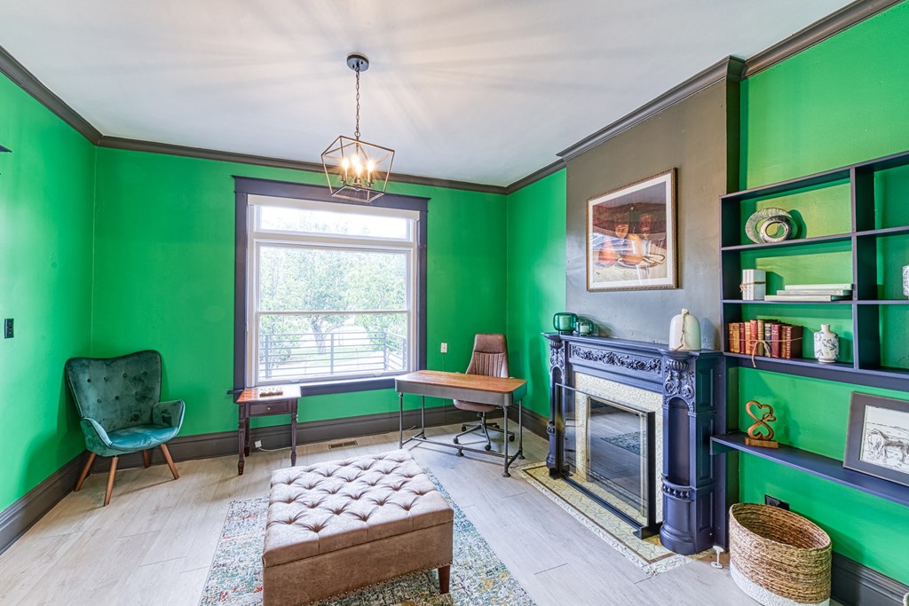 a living room with green walls and a fireplace     and a desk