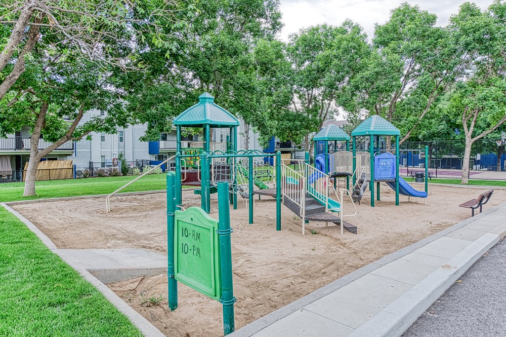 a playground with two swings and a bench in a park