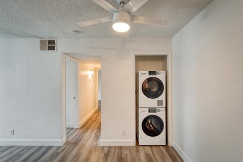 the living room of an apartment with a washing machine and a ceiling fan