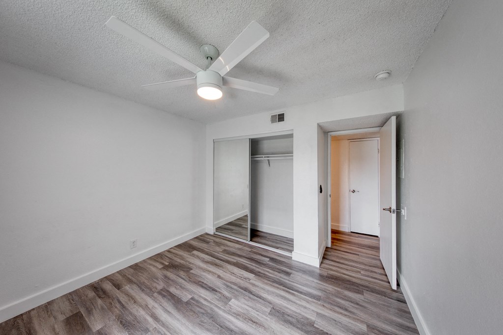 a bedroom with hardwood flooring and a ceiling fan
