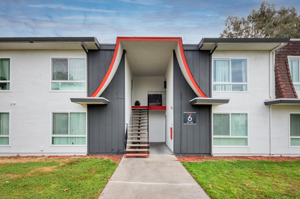 a building with grey and red walls and a staircase in front of it