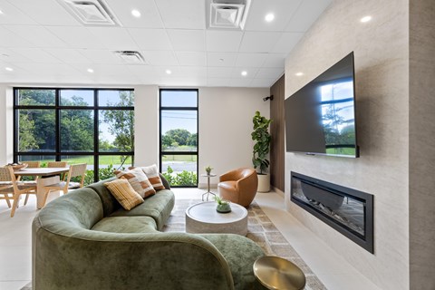 A modern living room with a green couch and a flat screen TV mounted on the wall.