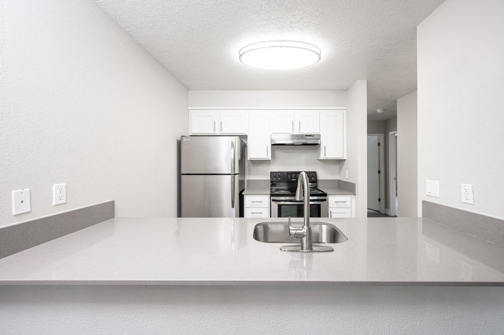 a kitchen with white countertops and a stainless steel refrigerator