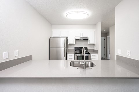 a kitchen with white countertops and a stainless steel refrigerator