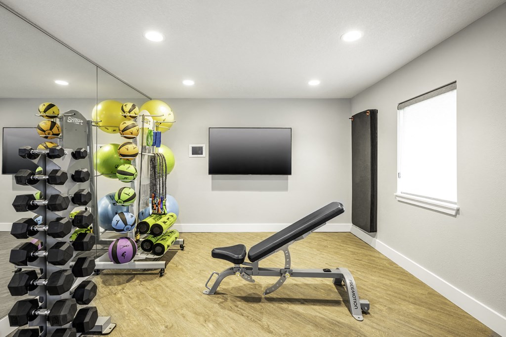 a home gym with a large mirror and a wall mounted tv