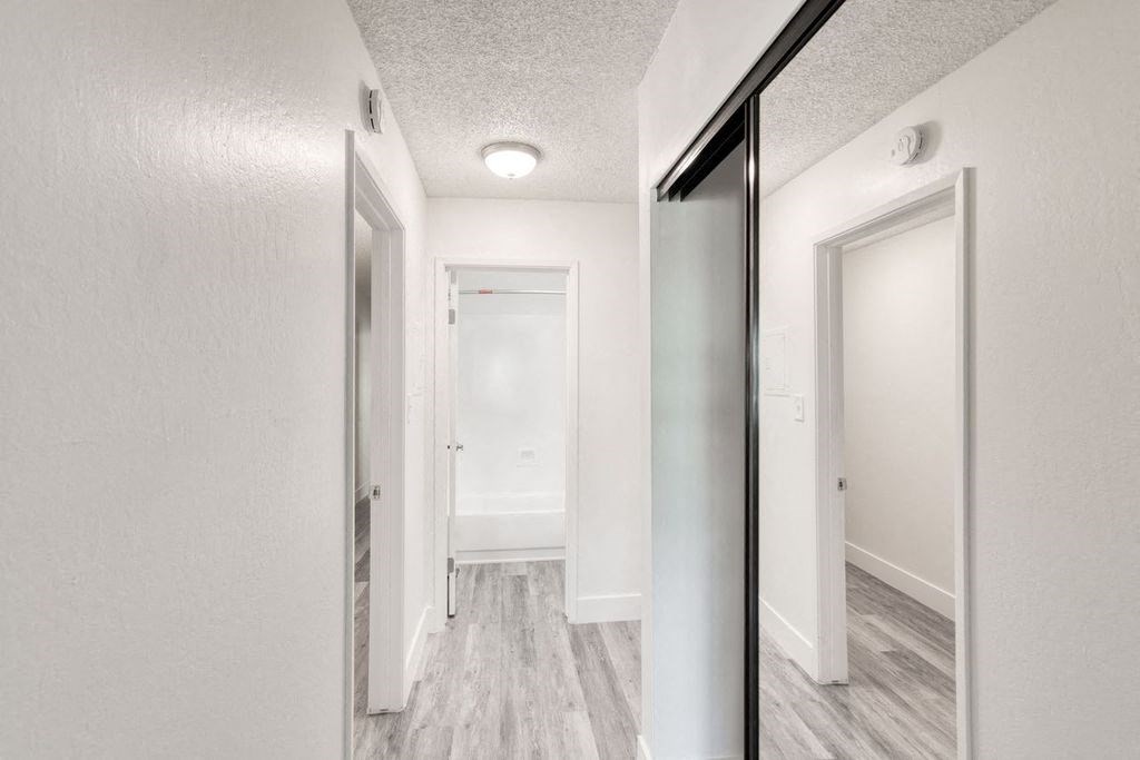 a bedroom with a large mirror and a hallway in the background