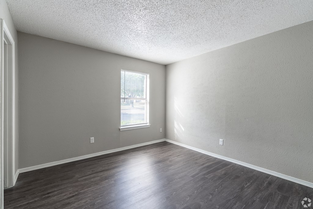 A room with a window and wooden flooring.