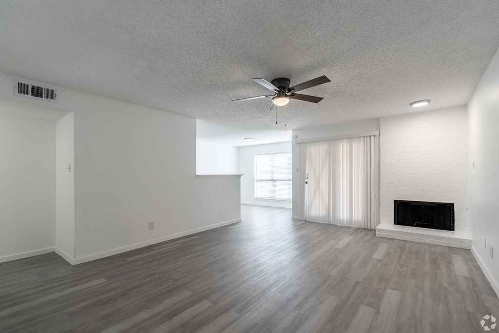 A spacious living room with a fireplace and a ceiling fan.