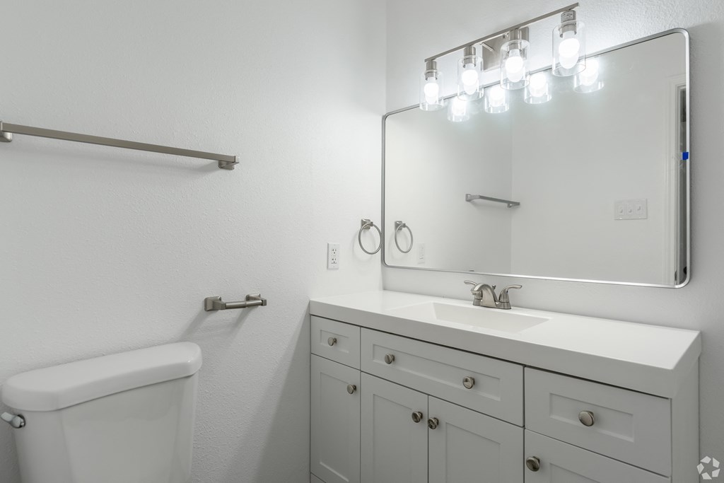 A white bathroom with a white toilet, sink, and vanity.
