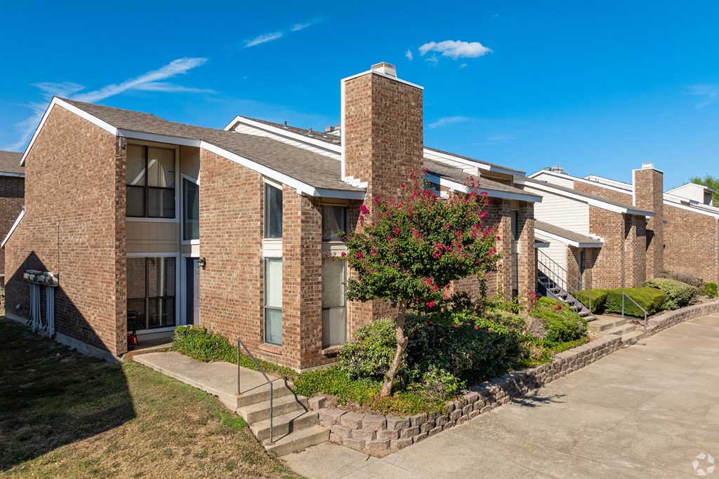 A row of brick apartment buildings with a tree in front.