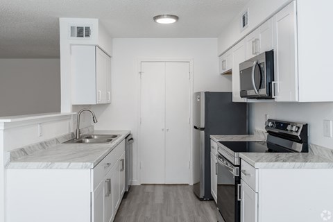 A kitchen with white cabinets and black appliances.