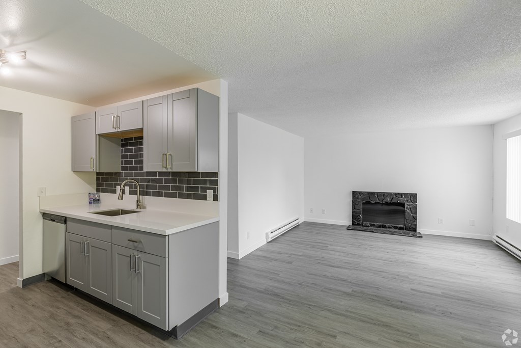 A kitchen with a sink and a fireplace in the living room.