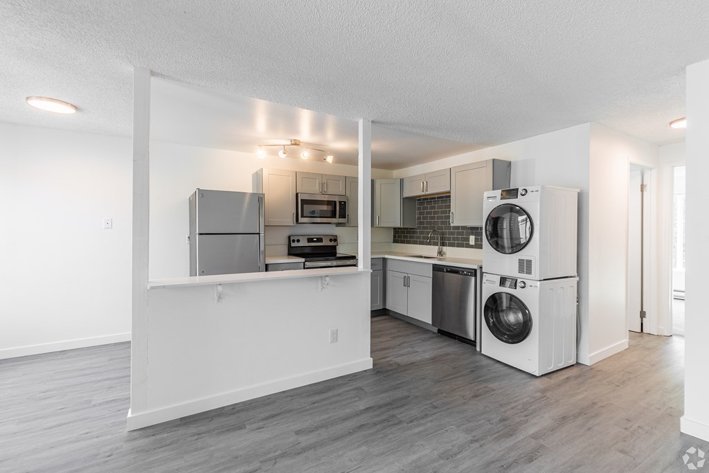 A kitchen with white appliances and a grey floor.