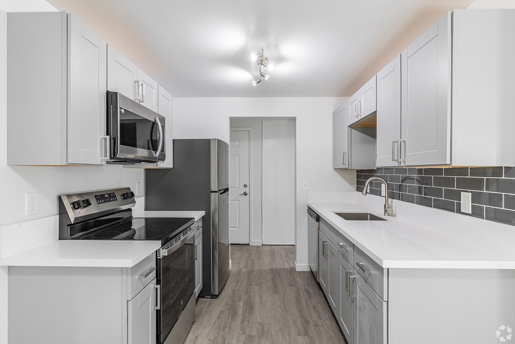 A kitchen with white cabinets and black appliances.