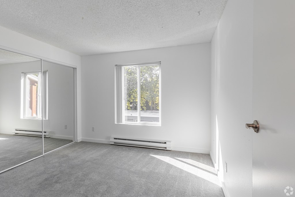 A white room with a door, window, and a mirror.