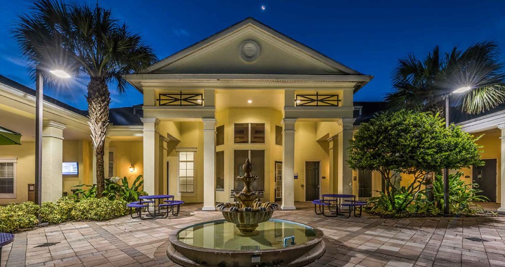 a courtyard with a fountain and a large building in the background