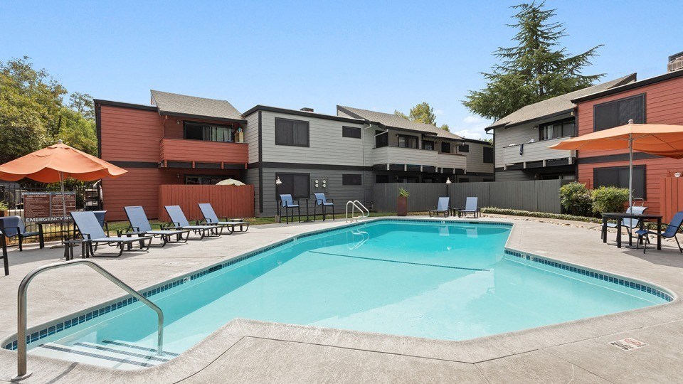 a pool with lounge chairs and umbrellas at the west end lodge apartments in beaum